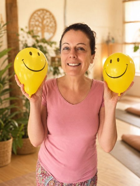 Magalie souriante tenant deux ballons jaunes décorés de visages souriants