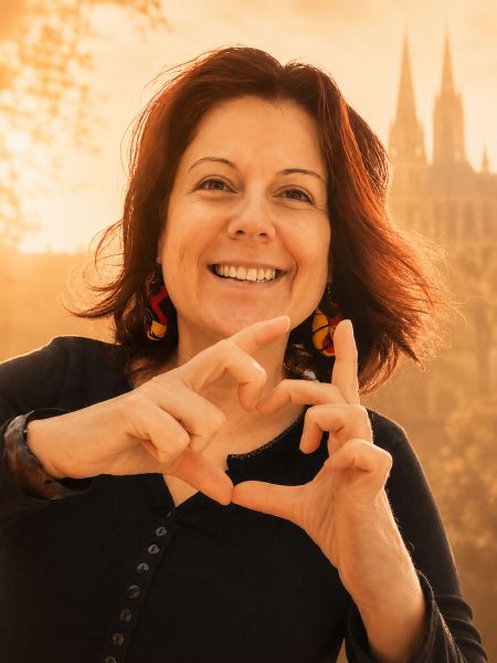 Femme souriante formant un cœur avec ses mains, avec la cathédrale de Chartres en arrière-plan